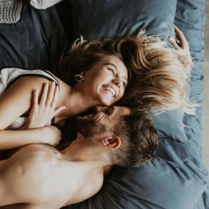 Bettbeziehung: Mann und Frau spielerisch und lächelnd im Bett zusammen